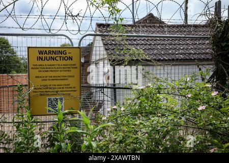 Ein Schild von MBR Acres auf dem Sicherheitszaun warnt die Demonstranten, dass der Protest aufgrund einer gerichtlichen Anordnung am Ende der Fabrik eingeschränkt werden könnte, die von Sicherheitskräften während der Demonstration beobachtet wird. Die Demonstranten blockierten das einzige Eingangstor, um zu verhindern, dass Arbeiter ausscheiden, um das Geschäft zu stören. Sie verlangen, dass die American Company, Marshal Bioresources (MBR) Acres, eine Beagle-Zuchtfarm, die Welpen für Tierversuchslabors bereitstellt, geschlossen wird. Die Demonstranten richteten „Camp Beagle“ ein, ein Protestlager, um Druck auf MBR auszuüben, direkt vor der Welpenfarm fast drei Jahre Stockfoto