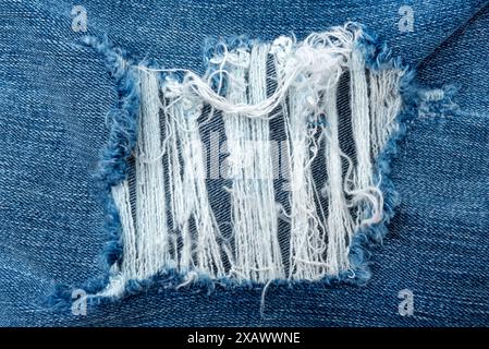 Nahaufnahme mit Loch in Jeans. Textur von verblasstem Denim Stockfoto