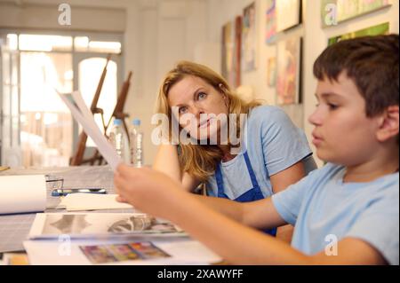 Kinder haben Kunstunterricht, Zeichnen, Malen mit dem Lehrer in der Werkstatt. Lehrer, der Schüler bei der Entwicklung künstlerischer Fähigkeiten begleitet. Stockfoto