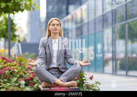 Professionelle Geschäftsfrau praktiziert Yoga und Meditation im Freien in der Stadt, um Stress abzubauen und den Fokus zu verbessern. Stockfoto