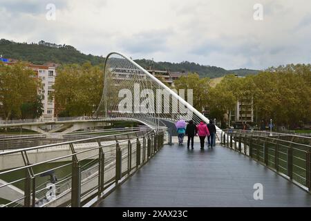 Bilbao, Spanien - 3. Oktober 2024; Touristen gehen im Regen über die Zubizuri-Brücke Stockfoto