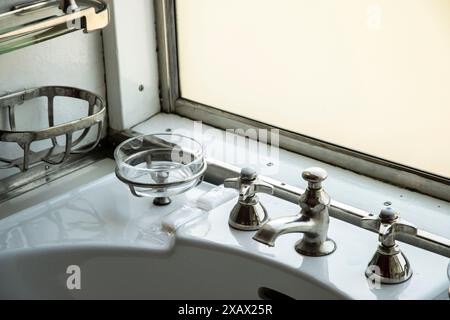 Alte antike Armatur im Retro-Stil mit Griffen und weißem Waschbecken im alten Zug Stockfoto