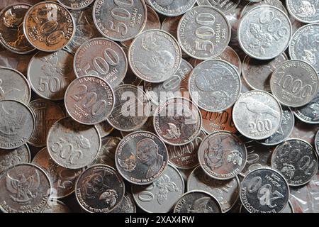 Eine Sammlung indonesischer Rupiah-Münzen in verschiedenen Stückelungen, darunter 500 und 200 Rupiah-Münzen, verstreut auf einer Oberfläche. Stockfoto