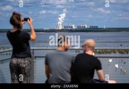 Cottbus, Deutschland. Juni 2024. Vom Aussichtsturm Merzdorf aus genießen Besucher bei sonnigem Wetter den Blick auf die Cottbuser Ostsee und das LEAG-Kraftwerk Jänschwalde. Die Überschwemmung des ehemaligen Tagebaus Cottbus-Nord begann Mitte April 2019. Quelle: Monika Skolimowska/dpa/Alamy Live News Stockfoto