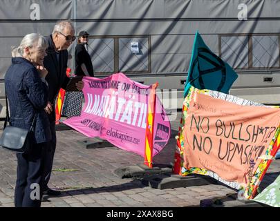 Passanten, die sich die Banner ansehen, die während des Protestes der „Sturmwarnung“ der Extinction Rebellion Finland am 7. Juni 2024 in der Innenstadt von Helsinki gezeigt wurden. Stockfoto