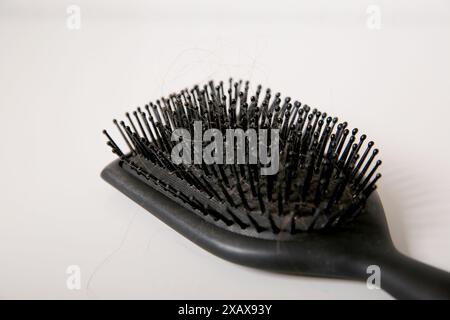 Nahaufnahme einer benutzten schmutzigen Haarbürste voller Haare auf weißem Tisch, Haarausfall-Problem-Konzept Stockfoto