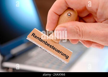 Rentenbesteuerung gedruckt auf Holzstempel eine Hand hält einen Holzstempel mit dem Aufdruck Rentenbesteuerung *** Pensionsbesteuerung gedruckt auf einem Holz Stockfoto