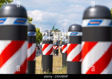 Es gibt eine Reihe rot-weiß gestreifter Barrieren auf der Straße. Im Hintergrund ist das Brandenburger Tor zu sehen. Die Schranken sind in einer Reihe angeordnet, Stockfoto