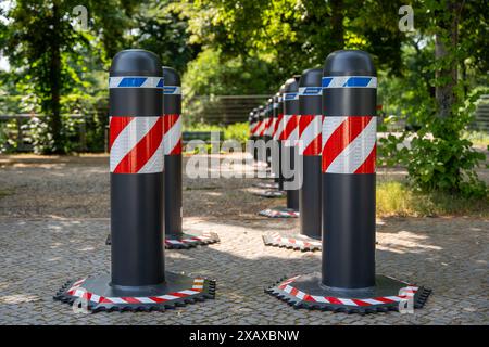 Eine Reihe von schwarzen und roten und weißen Barrieren sind in einem Park angeordnet. Die Barrieren sind hintereinander angeordnet, wobei einige von ihnen höher sind als andere Stockfoto