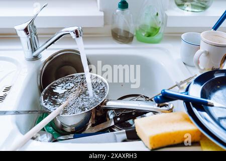 Ungewaschenes Geschirr auf einem Stapel auf dem Küchentisch in der Nähe des Waschbeckens Stockfoto