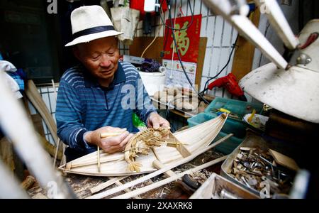 (240609) -- SHANGHAI, 9. Juni 2024 (Xinhua) -- dieses Aktenfoto vom 24. April 2017 zeigt Zhang Fucheng, der ein Holzmodell eines Drachenbootes im ostchinesischen Shanghai herstellt. Die aus der Ming-Dynastie (1368–1644) stammenden Drachenbootfahrten in Luodian, im ostchinesischen Shanghai Baoshan District gelegen, haben sich mit langanhaltender Lebendigkeit weiterentwickelt. Heute ist die Drachenbootfahrt in Luodian zu einer Kultveranstaltung für die Volksbräuche während des Drachenbootfestivals in Shanghai geworden. Es wurde 2008 als nationales immaterielles Kulturerbe gelistet. Im Laufe der Jahre kamen Zhang Guomin und Zhang Guozhong aus Stockfoto