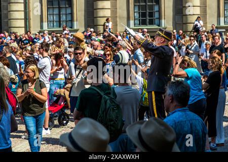 Der Dirigent der Kavallerie-Band steht auf einer Plattform inmitten der Touristen und leitet das Konzert mit Marschmusik und Abba-Liedern. Zeremonie der Kaisergarde im Königspalast von Stockholm. Wachwechsel vor dem schwedischen Königspalast in Stockholm mit musikalischer Begleitung der berittenen Band. Yttre borggården, Stockholm, Schweden Stockfoto