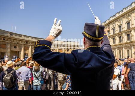 Der Dirigent der Kavallerie-Band steht auf einer Plattform inmitten der Touristen und leitet das Konzert mit Marschmusik und Abba-Liedern. Zeremonie der Kaisergarde im Königspalast von Stockholm. Wachwechsel vor dem schwedischen Königspalast in Stockholm mit musikalischer Begleitung der berittenen Band. Yttre borggården, Stockholm, Schweden Stockfoto