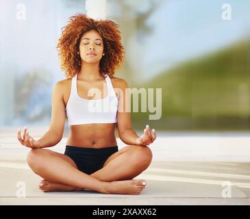 Frau, entspannen und Meditation mit Zen für Bewegung, spirituelles Wohlbefinden oder Fitness auf dem Boden auf der Terrasse. Ruhige oder junge Frau oder Yogi in Lotusstellung Stockfoto