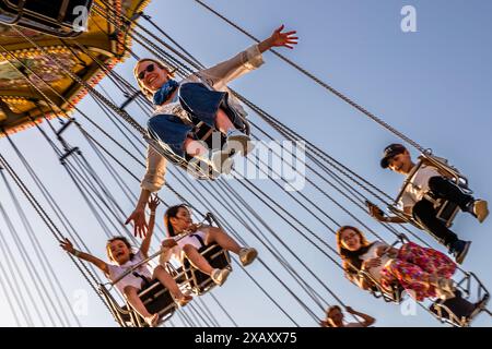 Detail mit Passagieren auf dem nostalgischen Kettenkarussell in der Abendsonne. Gröna Lund auf der Museumsinsel Djurgården ist Schwedens ältester Vergnügungspark. Sie wurde 1883 vom Deutschen Jacob Schultheiss gegründet. Der Vergnügungspark ist in einen alten und einen neuen Teil unterteilt. Kettenkarussell im Gröna Lund Tivoli. Saisonaler Vergnügungspark mit Achterbahnen und aufregenden Fahrgeschäften, Wettkampfspielen und Live-Konzerten. Djurgårdsstaden, Stockholm, Schweden Stockfoto