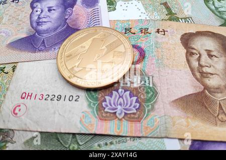 Nahaufnahme einer goldenen Litecoin-Münze auf einem Stapel chinesischer Yuan-Banknoten. Stockfoto