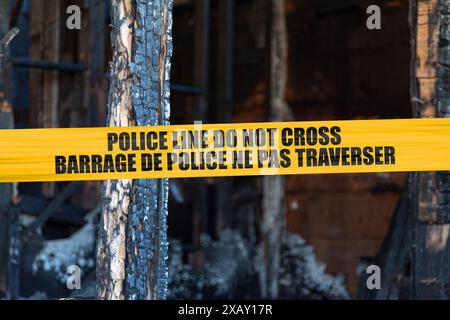 Das Haus wurde von einem Pyromanen mit einem Polizeiband auf den Boden gebrannt, auf dem auf Englisch "Police line do not Cross" und Französisch "Barrage de Police ne" geschrieben ist Stockfoto