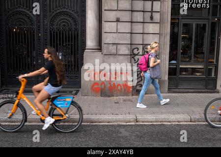 Barcelona, Spanien. Juni 2024. Ein Graffiti mit dem Slogan Tourist Go HOME wird gesehen, wenn Leihfahrräder vorbeifahren. Wie die meisten europäischen Hauptstädte lebt Barcelona zwischen der Notwendigkeit einer Tourismuswirtschaft, auf die es nicht verzichten kann, und der Ablehnung einer großen Gruppe von Bürgern gegen die für die Tourismusbranche typischen kulturellen Verzerrungen und Arbeitsplatzunsicherheiten. Slogans auf öffentlichen Plätzen aus der jüngsten Demonstration gegen die Überfüllung von Touristen existieren zusammen mit einer touristischen Aktivität, die nie ruht. Quelle: SOPA Images Limited/Alamy Live News Stockfoto