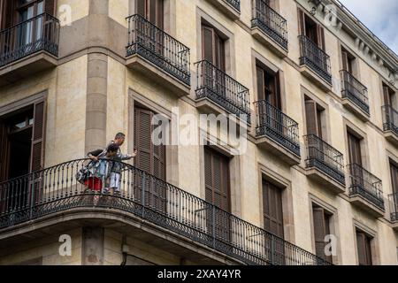 Barcelona, Spanien. Juni 2024. Ein asiatischer Tourist wird beobachtet, wie er Fotos von der beliebten Rambla Promenade vom Balkon seiner Wohnung macht. Wie die meisten europäischen Hauptstädte lebt Barcelona zwischen der Notwendigkeit einer Tourismuswirtschaft, auf die es nicht verzichten kann, und der Ablehnung einer großen Gruppe von Bürgern gegen die für die Tourismusbranche typischen kulturellen Verzerrungen und Arbeitsplatzunsicherheiten. Slogans auf öffentlichen Plätzen aus der jüngsten Demonstration gegen die Überfüllung von Touristen existieren zusammen mit einer touristischen Aktivität, die nie ruht. (Foto: Paco Freire/SOPA Images/SIPA USA) Credit: SIPA USA/Alamy Live News Stockfoto