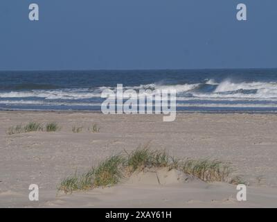 Ruhiger Strand mit Dünen und grasbewachsenen Sandhügeln vor dem hügeligen Meer, Juist, Ostfriesland, Deutschland Stockfoto