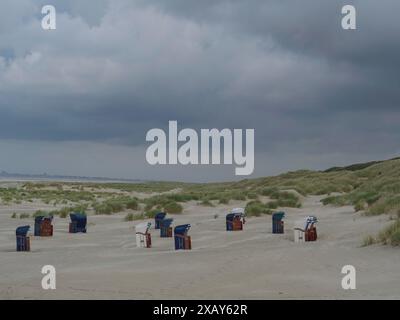 Verstreute Liegen am Sandstrand vor bewölktem Himmel und grasbewachsenen Dünen, Juist, ostfriesland, deutschland Stockfoto