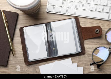 Lederner Visitenkartenhalter mit leeren Karten, Schreibwaren und Tastatur auf Holztisch, flach gelegt Stockfoto