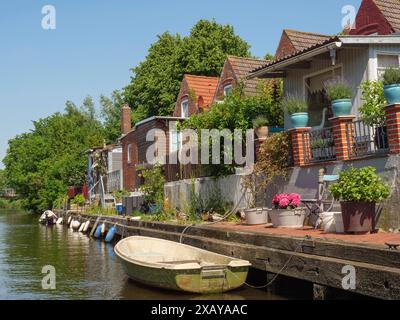 Reihenhäuser entlang des Kanals mit Booten am Ufer und Blumen auf den Balkonen, friedrichstadt, schleswig-holstein, deutschland Stockfoto