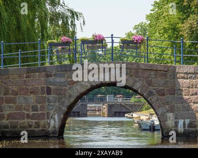 Historische Steinbrücke über einen Kanal mit Blumen und Booten im Wasser an einem sonnigen Tag, friedrichstadt, schleswig-holstein, deutschland Stockfoto