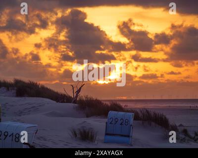 Liegestühle am Strand bei Sonnenuntergang, mit beeindruckenden Wolken am Himmel und Dünen im Hintergrund, Juist, ostfriesland, deutschland Stockfoto