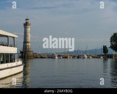 Leuchtturm im Hafen mit Booten am Steg, ruhiges Wasser und klarem Himmel an einem Sommertag, Lindau, Bodensee, Deutschland Stockfoto