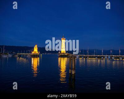 Nachtszene eines Hafens mit beleuchtetem Leuchtturm und Löwenskulptur im Wasser, Meersburg, Bodensee, Deutschland Stockfoto