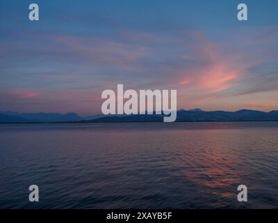 Romantischer Sonnenuntergang über einem ruhigen See, die Berge am Horizont unter einem bunten Himmel, Meersburg, Bodensee, Deutschland Stockfoto