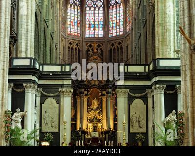 Ein atemberaubendes Kircheninnere mit prächtigem Buntglas und detaillierten Altarverzierungen, Gent, Belgien Stockfoto