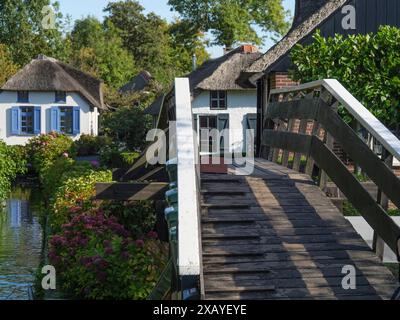 Eine Holzbrücke über einen Kanal, umgeben von gepflegten Gärten und charmanten Häusern, giethoorn, Niederlande Stockfoto