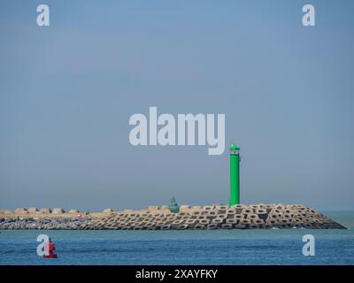 Grüner Leuchtturm auf einem Wellenbrecher im blauen Meer unter klarem Himmel, oostende, Belgien Stockfoto