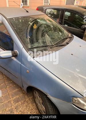 Cremona, Italien - 9. Juni 2024 staubiger Wagen, der nach einem Sandsturm auf einer Stadtstraße geparkt wurde und die Auswirkungen von Umweltverschmutzung und Wetter auf die Umwelt zeigt. Ur Stockfoto