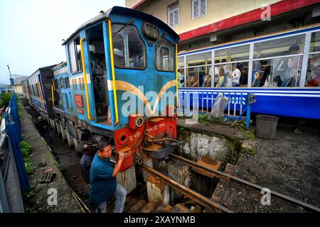 Ein Eisenbahnmitarbeiter sah, wie er an einer Toy Train-Dampflok am Bahnhof Darjeeling arbeitete. Die Darjeeling Himalayan Railway, auch bekannt als „Toy Train“, ist ein Schmalspurzug und wurde zwischen 1879 und 1881 gebaut. Die Bahn bewegt sich auf eine Höhe von 2.200 Metern (7.218 ft). Vier moderne Diesellokomotiven übernehmen den Großteil des Linienverkehrs; die täglichen Touristenzüge von Darjeeling nach Ghum (dem höchsten Bahnhof Indiens) werden jedoch von den alten Dampflokomotiven der B-Klasse abgewickelt. DHR wurde 1999 von der UNESCO zum Weltkulturerbe erklärt. Stockfoto