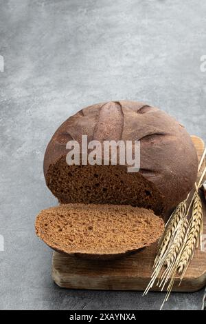 Geschnittenes Roggenbrot mit Ohren auf grauem Hintergrund Stockfoto