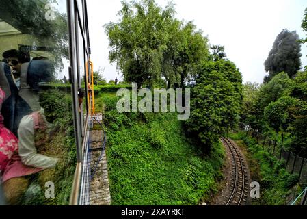 8. Juni 2024, Darjeeling, West Bengalen, Indien: Ein Spielzeugzug macht seine Reise durch die Stadt Darjeeling. Die Darjeeling Himalayan Railway, auch bekannt als „Toy Train“, ist ein Schmalspurzug und wurde zwischen 1879 und 1881 gebaut. Die Bahn bewegt sich auf eine Höhe von 2.200 Metern (7.218 ft). Vier moderne Diesellokomotiven übernehmen den Großteil des Linienverkehrs; die täglichen Touristenzüge von Darjeeling nach Ghum (dem höchsten Bahnhof Indiens) werden jedoch von den alten Dampflokomotiven der B-Klasse abgewickelt. Die DHR wurde von der UNESCO zum Weltkulturerbe erklärt Stockfoto