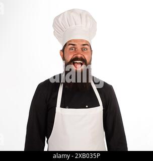 Porträt des glücklichen Küchenchefs in Uniform. Bärtiger Koch, Koch oder Bäcker in Küche Restaurant oder Hotel. Lächelnder männlicher Koch in Uniform, Kochmütze und Schürze. Profe Stockfoto