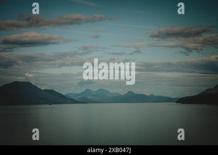 Dieses ruhige Foto fängt die ruhige Schönheit der Bergketten Alaskas in der Abenddämmerung ein, mit sanftem Licht, das das ruhige Wasser und die sanften Hügel, pe, beleuchtet Stockfoto