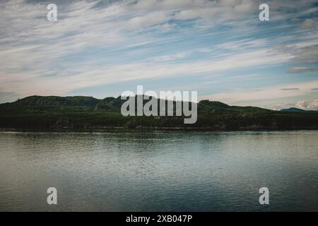 Dieses atemberaubende Foto zeigt die ruhige Wildnis Alaskas mit ruhigem Wasser, üppigen grünen Wäldern und einem lebendigen Himmel. Ideal für die Natur, t Stockfoto