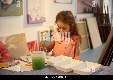 Ein junges Mädchen, das Aquarelle in einem Kunstunterricht malte. Die Kinderkünstlerin konzentriert sich auf ihre Arbeit während eines Workshops in einem Kunststudio. Stockfoto