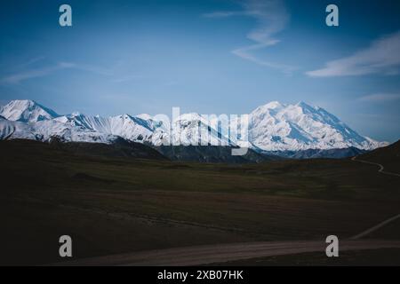 Tauchen Sie ein in die ruhige Schönheit der schneebedeckten Berge Alaskas. Diese Panoramaaufnahme erfasst die majestätischen Gipfel unter einem klaren blauen Himmel, Perfe Stockfoto