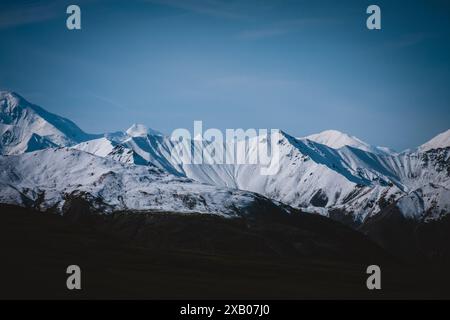 Erleben Sie die ruhige Schönheit der majestätischen schneebedeckten Berge Alaskas unter einem klaren blauen Himmel. Perfekt für Naturthemen, Abenteuer und Reisen, Stockfoto