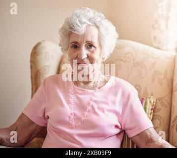 Porträt, ältere oder glückliche Frau zu Hause, um sich mit Wellness oder Selbstvertrauen auf dem Wohnzimmerstuhl zu entspannen. Wohnung, stolze oder ältere Dame, die in Frieden ruht Stockfoto