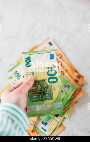 Geld zählen. Euroscheine aus nächster Nähe auf einem Marmorhintergrund zählen. Geldscheine und -Symbole. Hände, die Euro-Rechnungen zählen. Frauengehälter Stockfoto