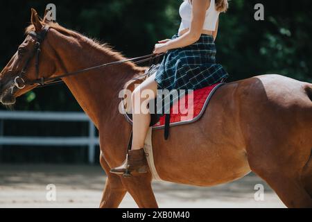 Eine junge Frau, die draußen auf einem Pferd reitet, in lässiger Kleidung an einem sonnigen Tag Stockfoto