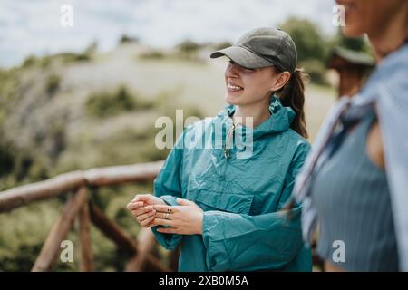 Junge Frau, die eine Wanderung in der Natur genießt, lächelt und Hut und Jacke trägt Stockfoto