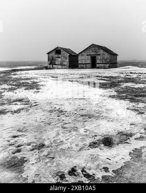 Zwei verlassene, heruntergekommene Scheunen in der kalten, winterlichen Tundra Kanadas. Stockfoto